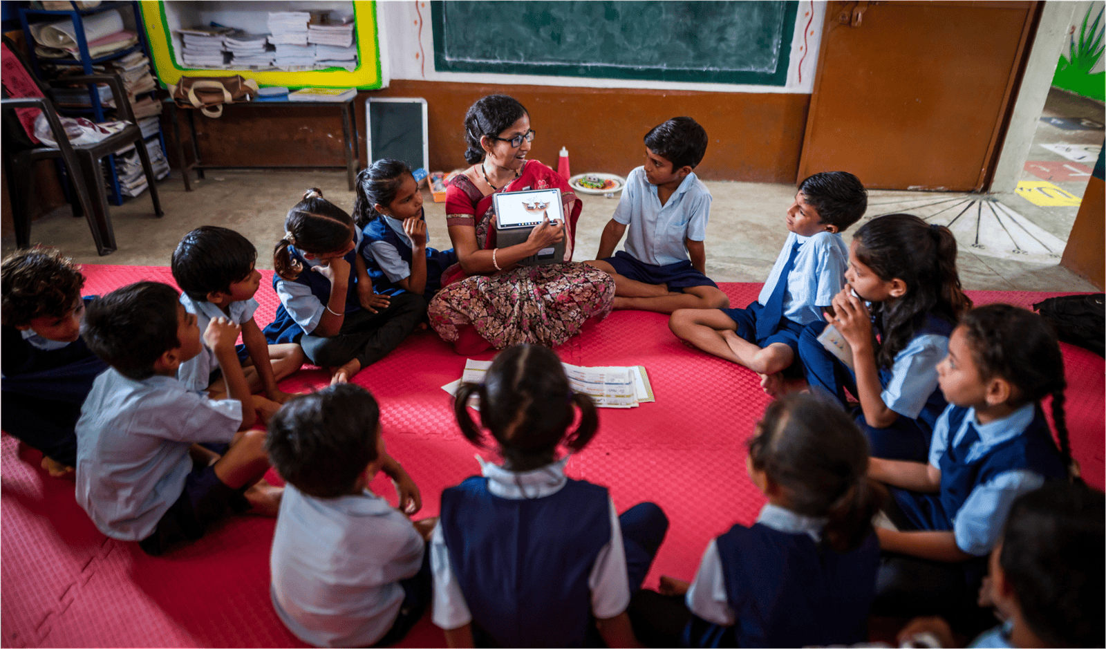 Teacher using digital device with children in circle